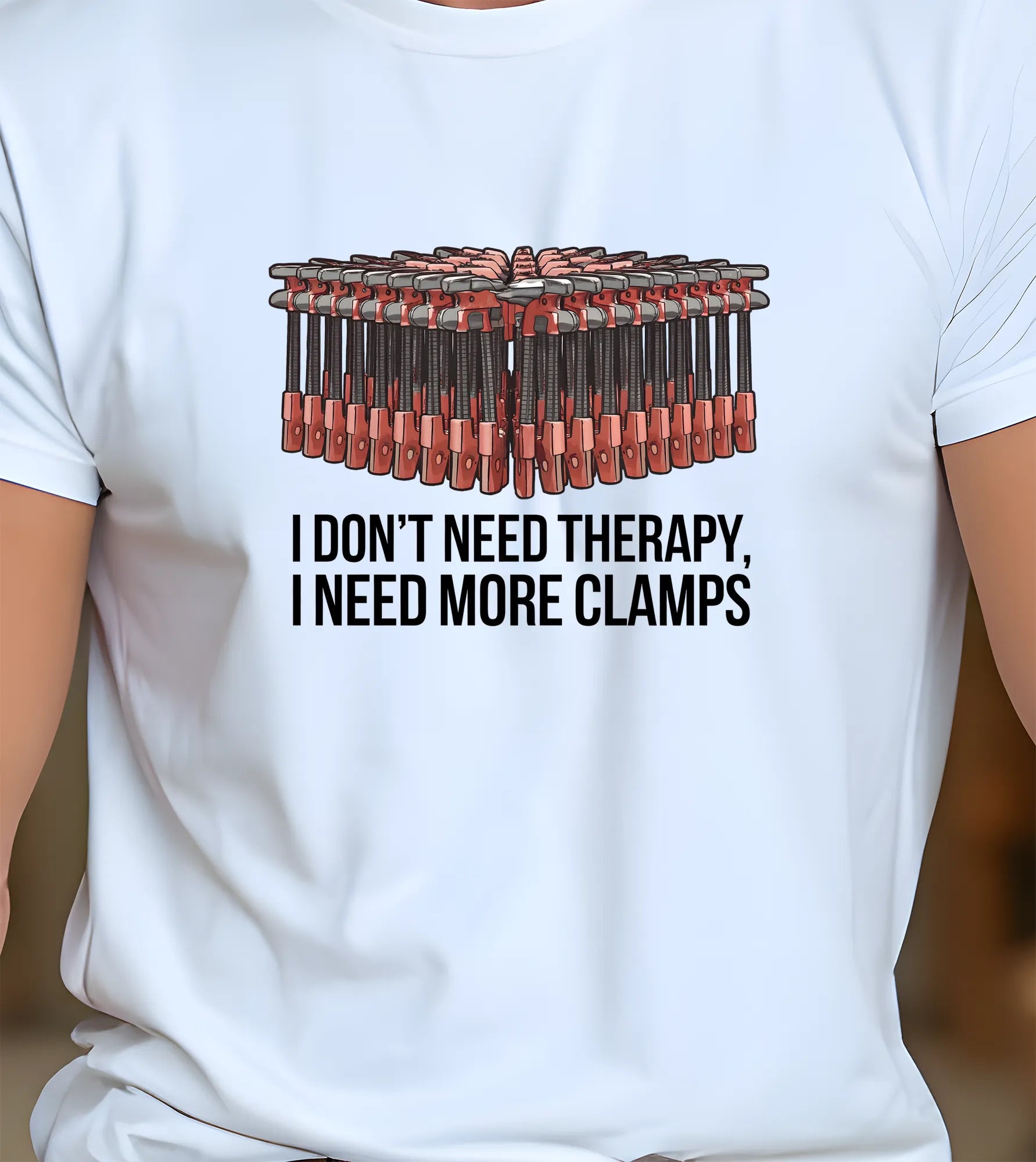 White t-shirt with graphic of clamps and text 'I don't need therapy, I need more clamps' on a plain background.